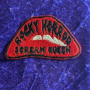 Peut inclure: Patch brodé rouge et noir avec les mots "Jaws" et "Scream Queen" en blanc.