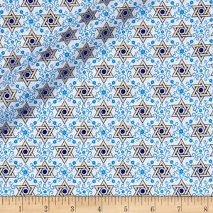 May include: Fabric with a repeating pattern of gold and navy blue Star of David symbols. The stars are set against a white background with a blue floral scroll design. The fabric is measured in inches.