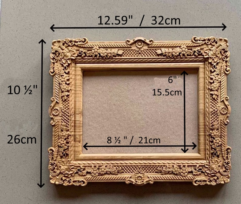 May include: A wooden picture frame with ornate carvings and a light brown finish. The frame measures 12.59 inches wide by 10 1/2 inches tall and has an interior opening of 8 1/2 inches wide by 6 inches tall.