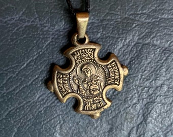 May include: A gold-toned metal pendant in the shape of a cross with a depiction of the Virgin Mary in the center. The cross has the words "СВ. РАВНОАПОСТОЛ. МАРИЯ" inscribed around the edges.