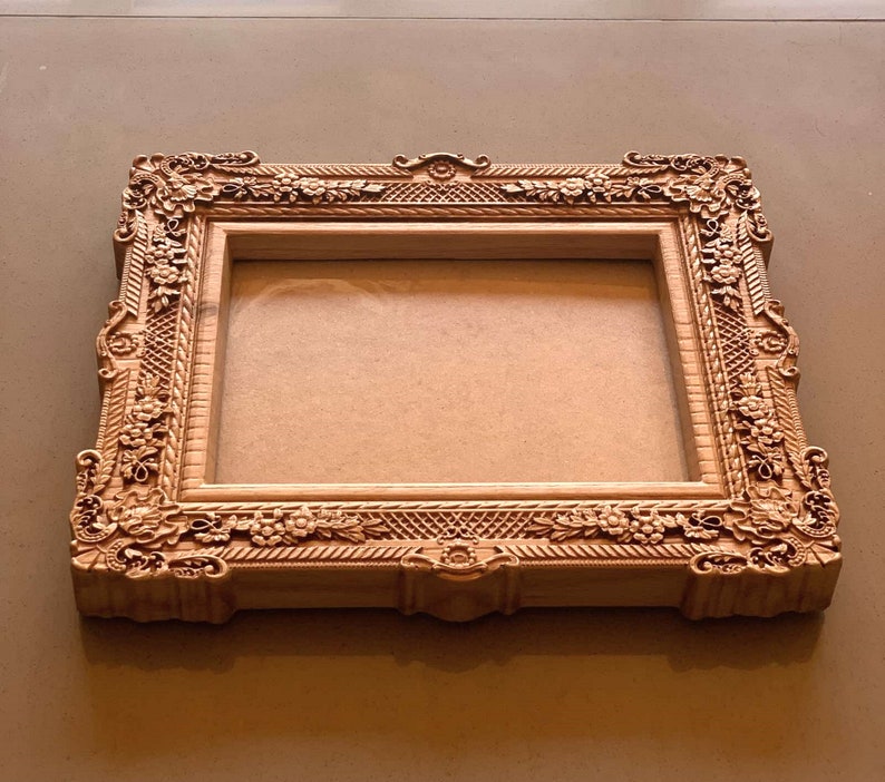 May include: A wooden picture frame with ornate carvings and a light brown finish.