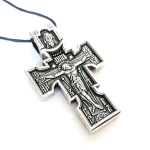K&ouml;nnte beinhalten: Ein silberfarbener Kreuzanh&auml;nger mit einer Darstellung von Jesus Christus am Kreuz. Das Kreuz ist mit kyrillischen Buchstaben und einem kleinen Bild von Jesu Kopf oben verziert.
