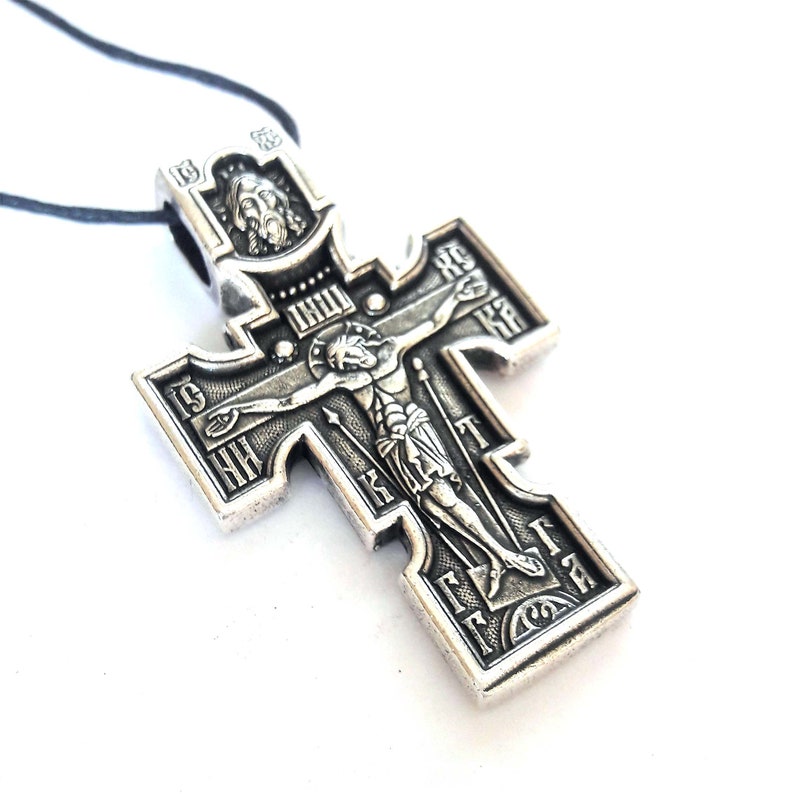 K&ouml;nnte beinhalten: Ein silberfarbener Kreuzanh&auml;nger mit einer Darstellung von Jesus Christus am Kreuz. Das Kreuz ist mit kyrillischen Buchstaben und einem kleinen Bild von Jesu Kopf oben verziert.