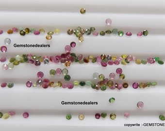 Puede incluir: Una colección de pequeñas piedras preciosas redondas multicolores, incluyendo rosa, verde y amarillo, esparcidas sobre una superficie blanca. El texto "Gemstonedealers" aparece dos veces en la superficie.