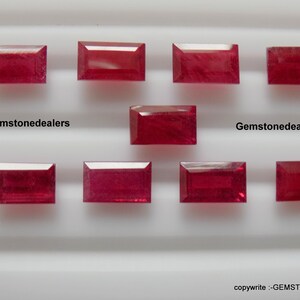 May include: Ten rectangular red gemstones, likely rubies, are arranged in two rows on a white surface. The text "Gemstonedealers" appears twice on the surface.