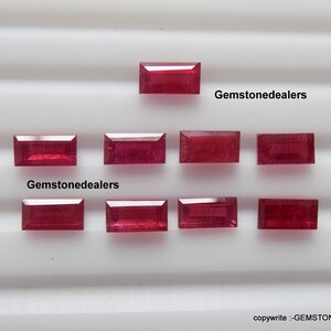 Puede incluir: Nueve piedras preciosas rectangulares rojas, probablemente rubíes, están dispuestas en una cuadrícula sobre una superficie blanca. El texto "Gemstonedealers" aparece dos veces en la imagen.