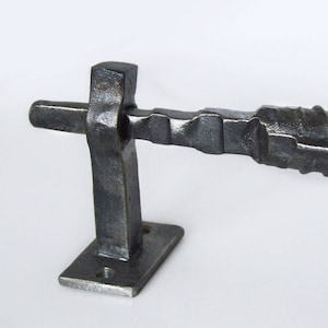 May include: A black metal door handle with a textured, twisted design. The handle is mounted to a square base.