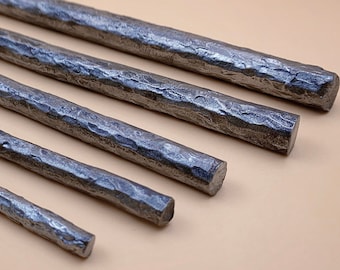Handsmidd 1 meter lång rundstång i texturerat stål. Detalj av hamrad metallstång. Industriell loftstil för hantverk. Verktyg. Råmaterial.