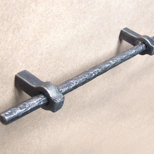 May include: A rustic, hammered iron drawer pull with a textured finish. The pull is approximately 6 inches long and has a simple, rectangular design.