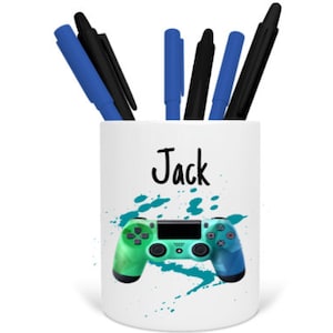 May include: White ceramic pencil holder with a green and blue video game controller graphic and the name "Jack" printed on the front.
