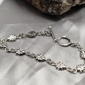 May include: A silver bracelet with a toggle clasp and decorative flower-shaped charms.