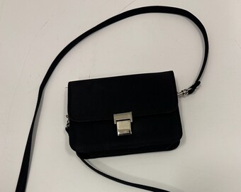 May include: A small black crossbody bag with a silver clasp closure and a long adjustable strap.