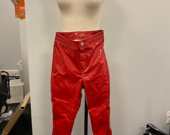 May include: Red patent leather pants with white side stripes. The pants are on a mannequin.