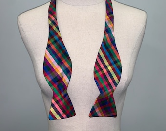 May include: A colorful bow tie with a checkered pattern in shades of pink, green, blue, yellow, and red.