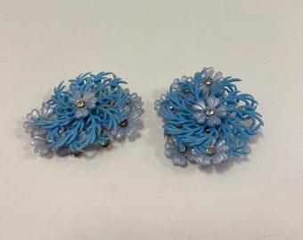 May include: A pair of blue and white flower-shaped earrings with rhinestones in the center of each flower.