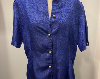 May include: A blue button-up blouse with a swirling pattern and gold buttons.