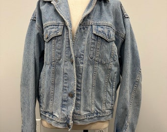 May include: A light blue denim jacket with a button closure and two front pockets.