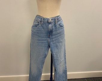 May include: Light blue denim jeans with a straight leg fit. The jeans have a classic five-pocket style and a button fly.