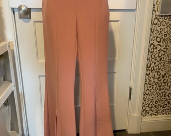 May include: A pair of dusty rose wide-leg pants with a high waist and a slit at the bottom of each leg.
