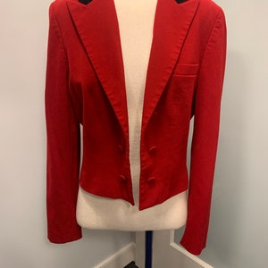 May include: A red blazer with a black velvet collar. The blazer has a double-breasted closure and long sleeves.