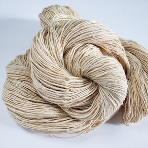 May include: A skein of natural beige yarn, made from a blend of linen and silk, is loosely wound into a ball shape.