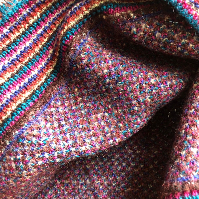 May include: Close-up of a brown, blue, and pink knitted fabric with a striped pattern. The fabric is soft and textured.