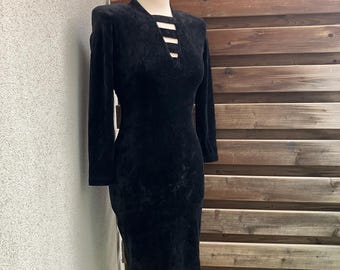 Könnte beinhalten: Ein schwarzes Samtkleid mit langen Ärmeln und einem Ausschnitt mit Cut-Out-Detail.