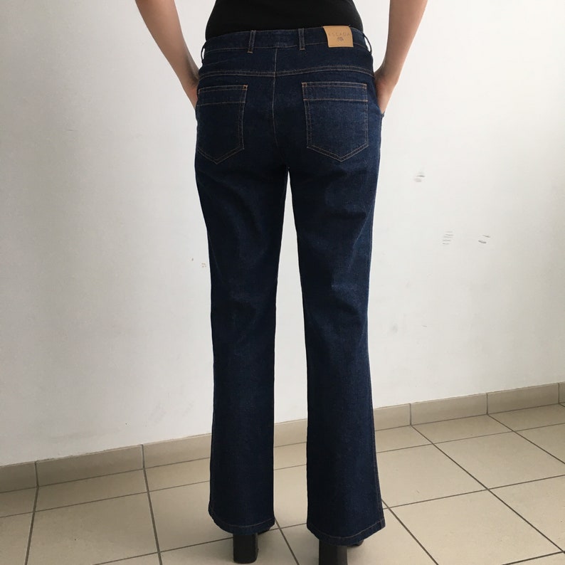 May include: Dark blue denim jeans with a straight leg fit. The jeans have a classic five-pocket style and a button closure.