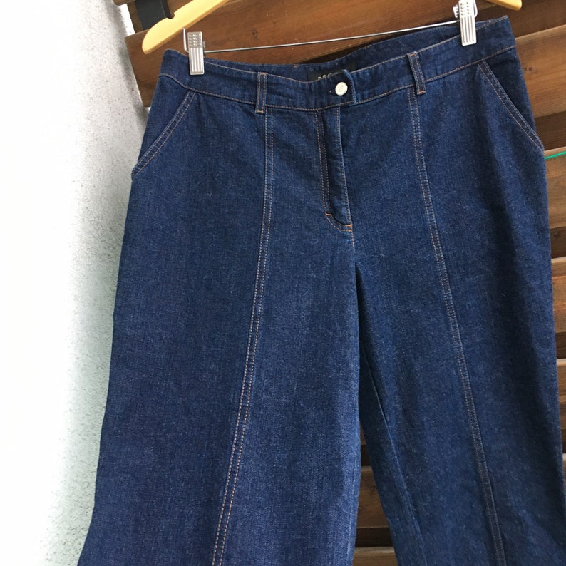 May include: Dark blue denim wide-leg pants with a button closure and a straight leg.