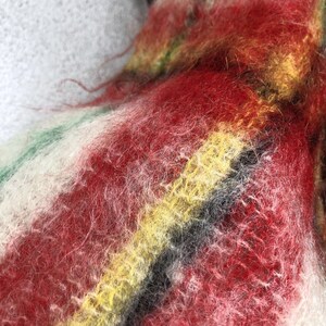 May include: Close-up of a multi-coloured fuzzy fabric with stripes of red, white, yellow, and black.