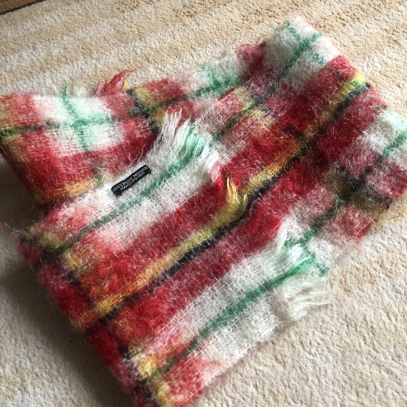 May include: Red, white, green and yellow plaid scarf with a frayed edge. The scarf has a black tag that reads "100% Pure Mohair Made in Scotland".