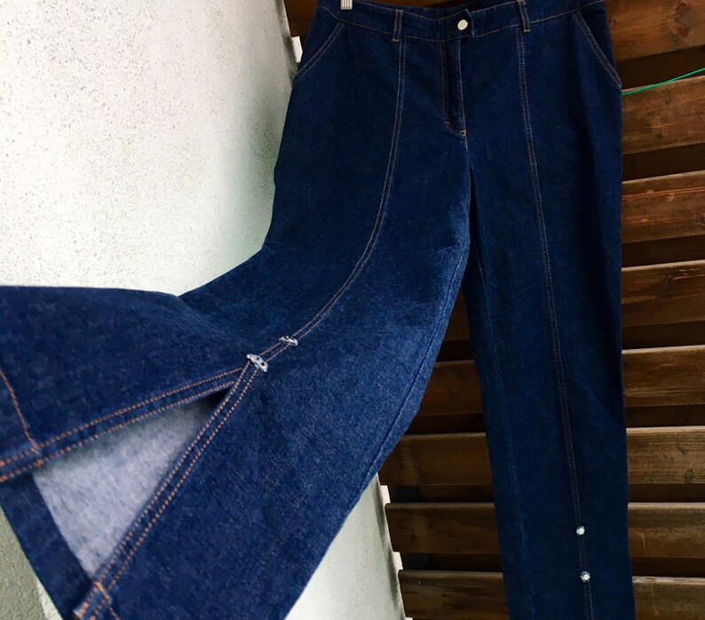 May include: A pair of dark blue denim jeans with a slit on the front of each leg. The jeans have a straight leg and a high waist.