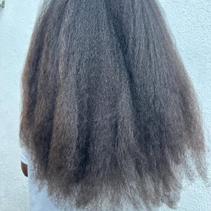 May include: A person with long, dark, and straight hair. The hair is styled in a simple, sleek way, with no visible parting or styling products.
