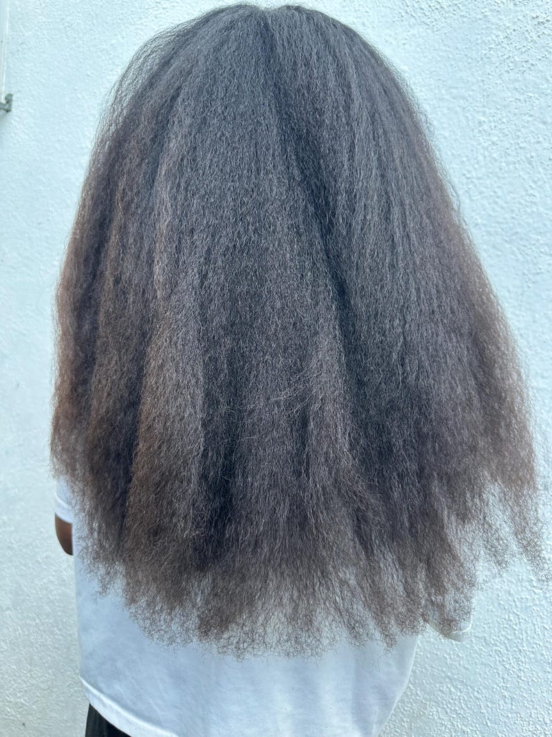 May include: A person with long, dark, and straight hair. The hair is styled in a simple, sleek way, with no visible parting or styling products.