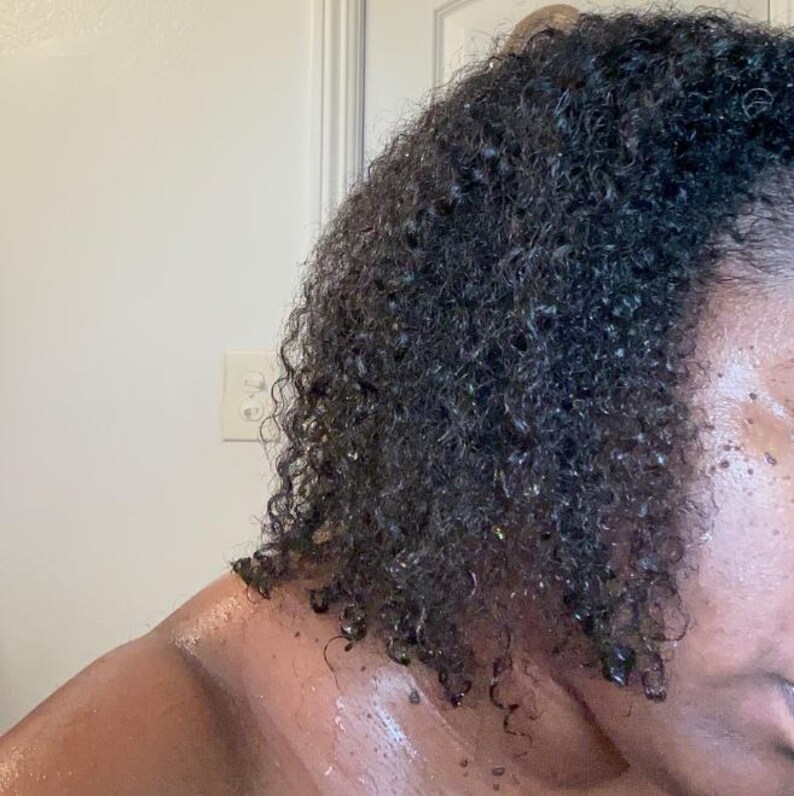 May include: Close-up of a person's dark brown curly hair with a wet look, showing the texture and definition of the curls.