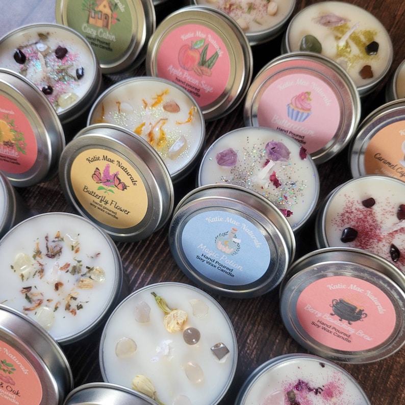 Puede incluir: Surtido de peque&ntilde;as velas de cera de soja hechas a mano en latas de metal. Cada vela tiene un aroma y un dise&ntilde;o &uacute;nicos, incluyendo "Cozy Cabin", "Apple Pecan Sage", "Butterfly Flower", "Magic Potion" y "Berry Beatching Brew".