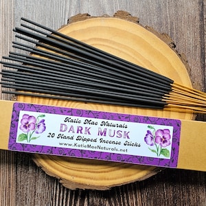 May include: A box of 20 hand-dipped incense sticks with a purple and black label that says "Katie Mae Naturals Dark Musk 20 Hand Dipped Incense Sticks www.KatieMaeNaturals.net".
