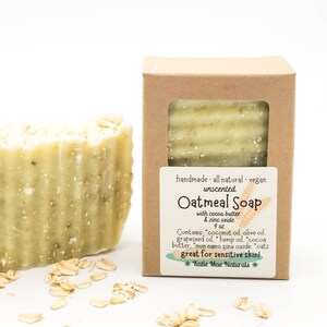 May include: A bar of unscented oatmeal soap with cocoa butter and zinc oxide. The soap is in a brown cardboard box with a white label that reads "handmade all natural vegan unscented Oatmeal Soap with cocoa butter & zinc oxide 4 oz Contains: coconut oil, olive oil, grapeseed oil, hemp oil, cocoa butter, non nano zinc oxide, oats great for sensitive skin! *Katie Mae Naturals*"