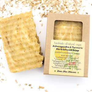 May include: A bar of handmade, all-natural, vegan Ashwagandha & Turmeric Herb Infused Soap, scented in midseason orange. The soap is 4 oz and contains saponified oils of coconut, olive, and sunflower, ashwagandha oil, kokum butter, midseason orange essential oil, ashwagandha root powder, turmeric root powder, and is organic. The soap is packaged in a brown cardboard box with a label that says "Katie Mae Naturals".