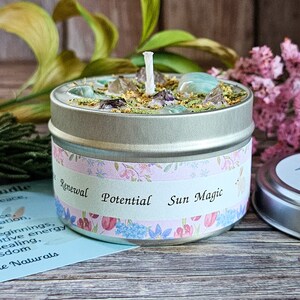 Peut inclure: Une bougie en bo&icirc;te argent&eacute;e avec une m&egrave;che blanche et des cristaux verts, transparents et violets incrust&eacute;s dans la cire. L'&eacute;tiquette sur la bo&icirc;te indique "Renouvellement Potentiel Magie du Soleil".