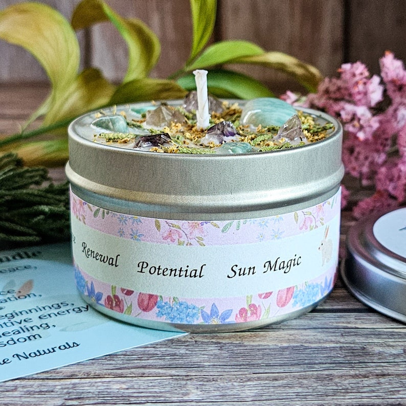 Peut inclure: Une bougie en bo&icirc;te argent&eacute;e avec une m&egrave;che blanche et des cristaux verts, transparents et violets incrust&eacute;s dans la cire. L'&eacute;tiquette sur la bo&icirc;te indique "Renouvellement Potentiel Magie du Soleil".