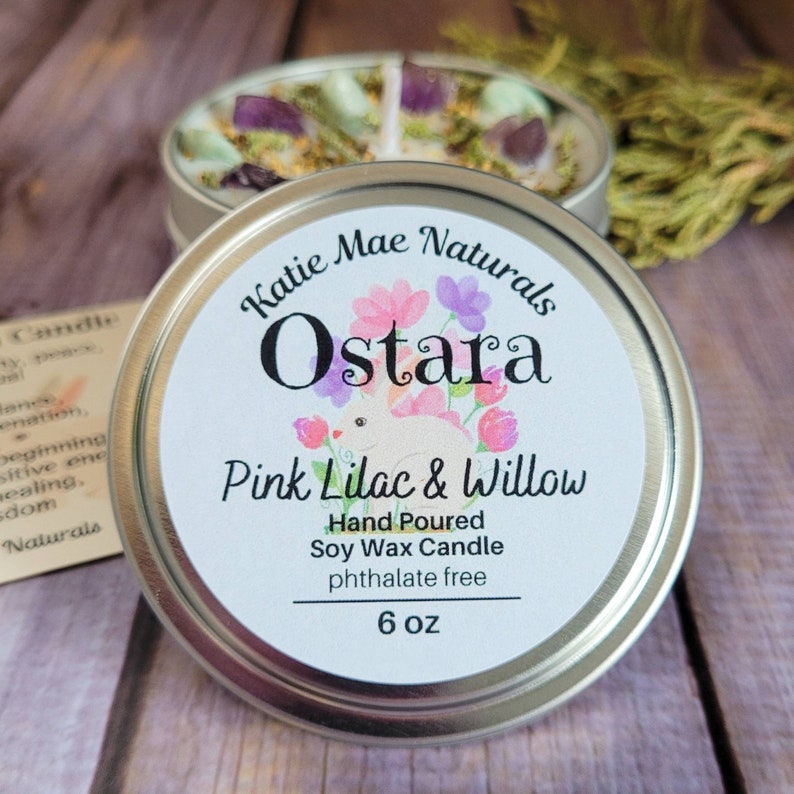 Peut inclure: Une bougie en cire de soja de 170 grammes dans un r&eacute;cipient en &eacute;tain avec une &eacute;tiquette blanche. L'&eacute;tiquette indique "Katie Mae Naturals Ostara Pink Lilac & Willow Hand Poured Soy Wax Candle phthalate free".