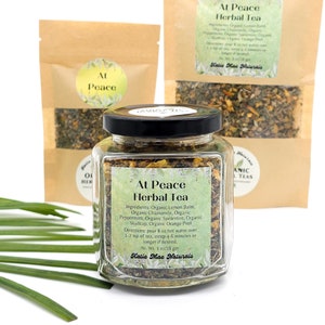 May include: A glass jar filled with a blend of dried herbs for herbal tea. The label reads "At Peace Herbal Tea" and lists the ingredients: Organic Lemon Balm, Organic Chamomile, Organic Peppermint, Organic Spearmint, Organic Skullcap, Organic Orange Peel. Directions for brewing the tea are also included. The jar is sitting on a white surface with green leaves.