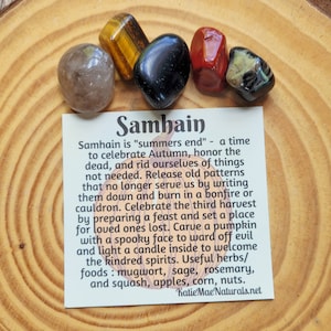 May include: A card with the word "Samhain" written in large, bold letters. The card explains the meaning of Samhain, a Celtic holiday celebrating the end of summer and the beginning of autumn. The card also lists herbs and foods associated with the holiday, such as mugwort, sage, rosemary, squash, apples, corn, and nuts.
