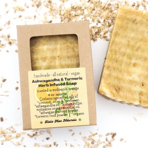 May include: A brown cardboard box with a white label that reads "handmade all natural vegan Ashwagandha & Turmeric Herb Infused Soap scented in midseason orange 4 oz (approx.) Contains saponified oils of coconut, olive, & sunflower, ashwagandha oil, kokum butter, midseason orange essential oil, ashwagandha root powder, turmeric root powder organic *Katie Mae Naturals*"