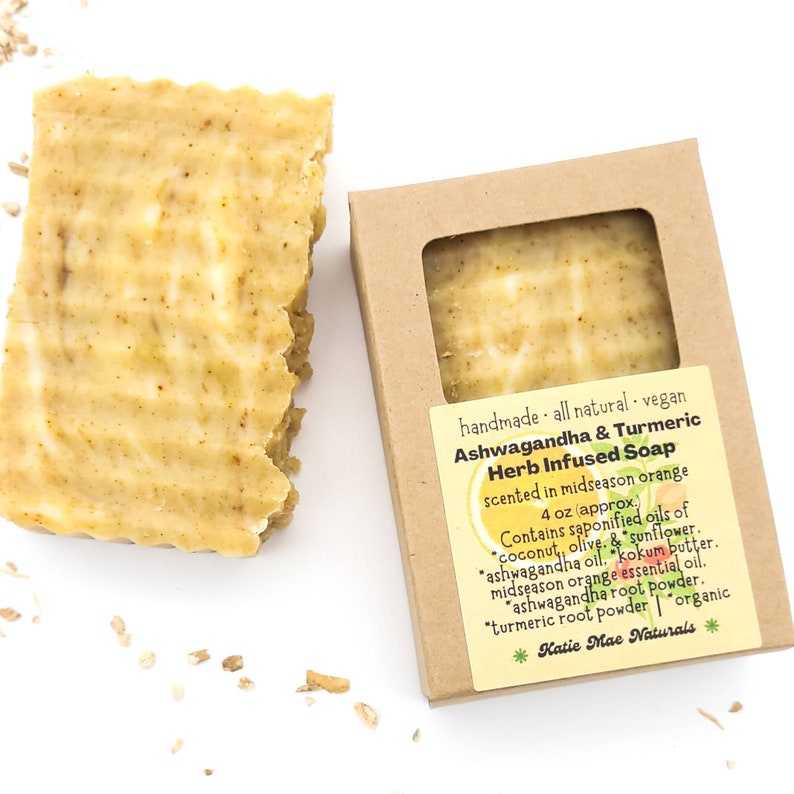 May include: A bar of handmade, vegan, ashwagandha and turmeric herb infused soap, scented in midseason orange. The soap is 4 ounces and contains saponified oils of coconut, olive, sunflower, ashwagandha, kokum butter, midseason orange essential oil, ashwagandha root powder, turmeric root powder, and is organic. The soap is packaged in a brown box with a label that says "Katie Mae Naturals".