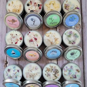 Puede incluir: Surtido de 18 peque&ntilde;os tarros de velas con diversos aromas y elementos decorativos. Los tarros est&aacute;n dispuestos en forma de cuadr&iacute;cula sobre una superficie de madera. Algunos de los aromas incluyen "Canela en Rama", "Musk Oscuro", "Ang&eacute;lica", "Ar&aacute;ndanos con Cobertura", "Poci&oacute;n M&aacute;gica", "Miel y Vainilla Polvo de Amor", "Jard&iacute;n de Luna", "Zarzamora y Salvia", y "Lluvia de Primavera".