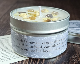 May include: A silver candle tin with a white candle and crystals inside. The label reads: "Ambitious, determined, responsible, organized, stable, smart, practical, confident, grounded, working, successful, loyal, inspiring, powerful".