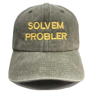 以下が含まれることがあります： オリーブグリーンの野球帽。黄色で「SOLVEM PROBLER」と刺繍されています。カーブしたつばと、クラシックな6パネルのデザインです。生地は少し色あせたヴィンテージ感があります。