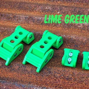 May include: Two lime green hinged latch mechanisms with three circular holes on the top plate and two smaller lime green mounting brackets with silver screws. The text LIME GREEN is printed in the upper right corner of the image.